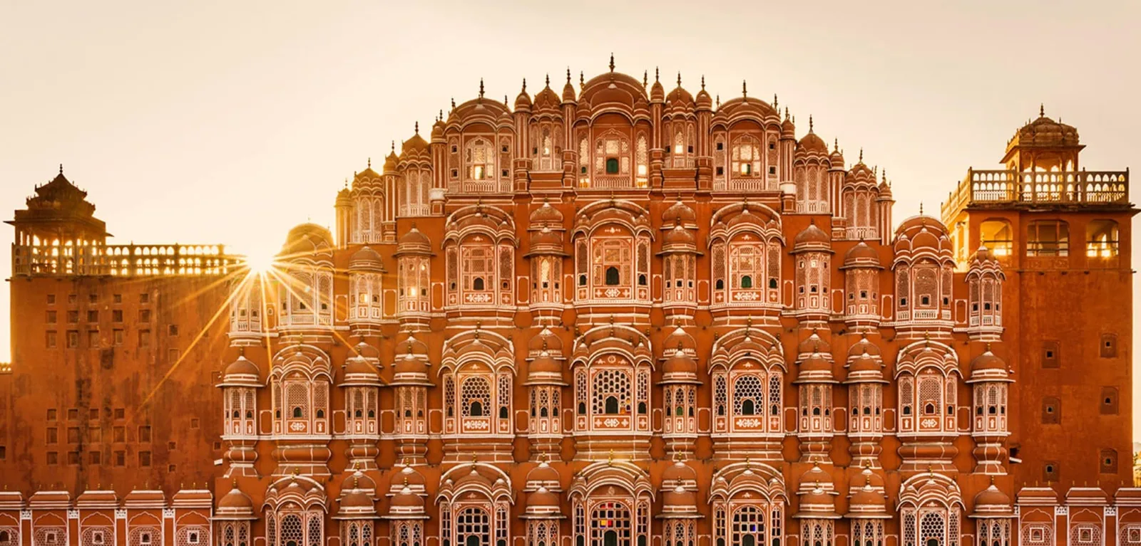 Fachada detalhada do Palácio dos Ventos em Jaipur, Índia, iluminada pelo sol ao fundo, ilustrando a complexidade de mercados internacionais que afetam o tarifeço dos EUA nas exportações.