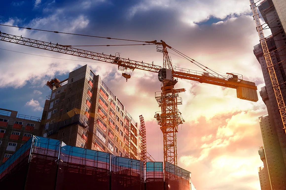 Guindaste e prédios em construção sob um céu nublado, ilustrando os impactos da Reforma Tributária na construção civil.