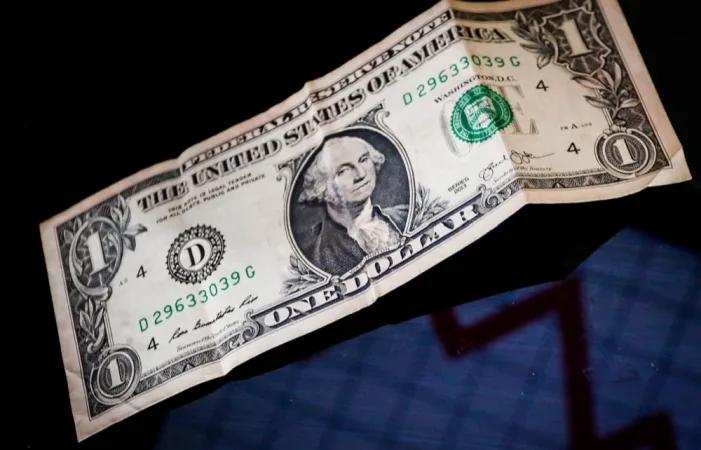 Nota de um dólar amassada sobre fundo escuro, ilustrando a flutuação cambial e o impacto no caixa empresarial.