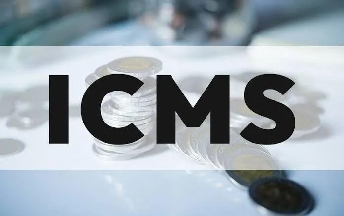 Pilha de moedas sobre a mesa com a palavra ICMS em destaque, ilustrando créditos tributários para empresas.