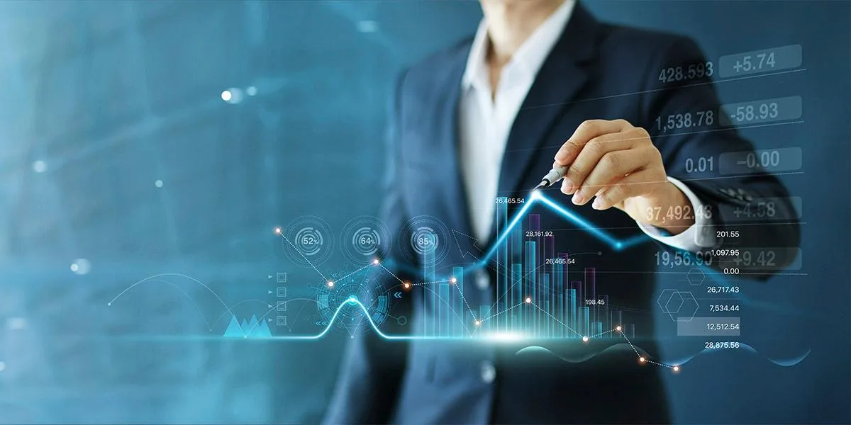 Profissional de terno aponta para gráficos financeiros digitais, ilustrando a Reforma Tributária que mexe na estratégia dos negócios.