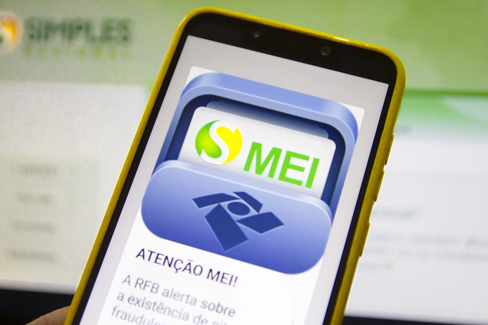 Smartphone com capa amarela exibindo na tela o aplicativo do MEI, relacionado à regularização de dívidas e Transação PGFN.