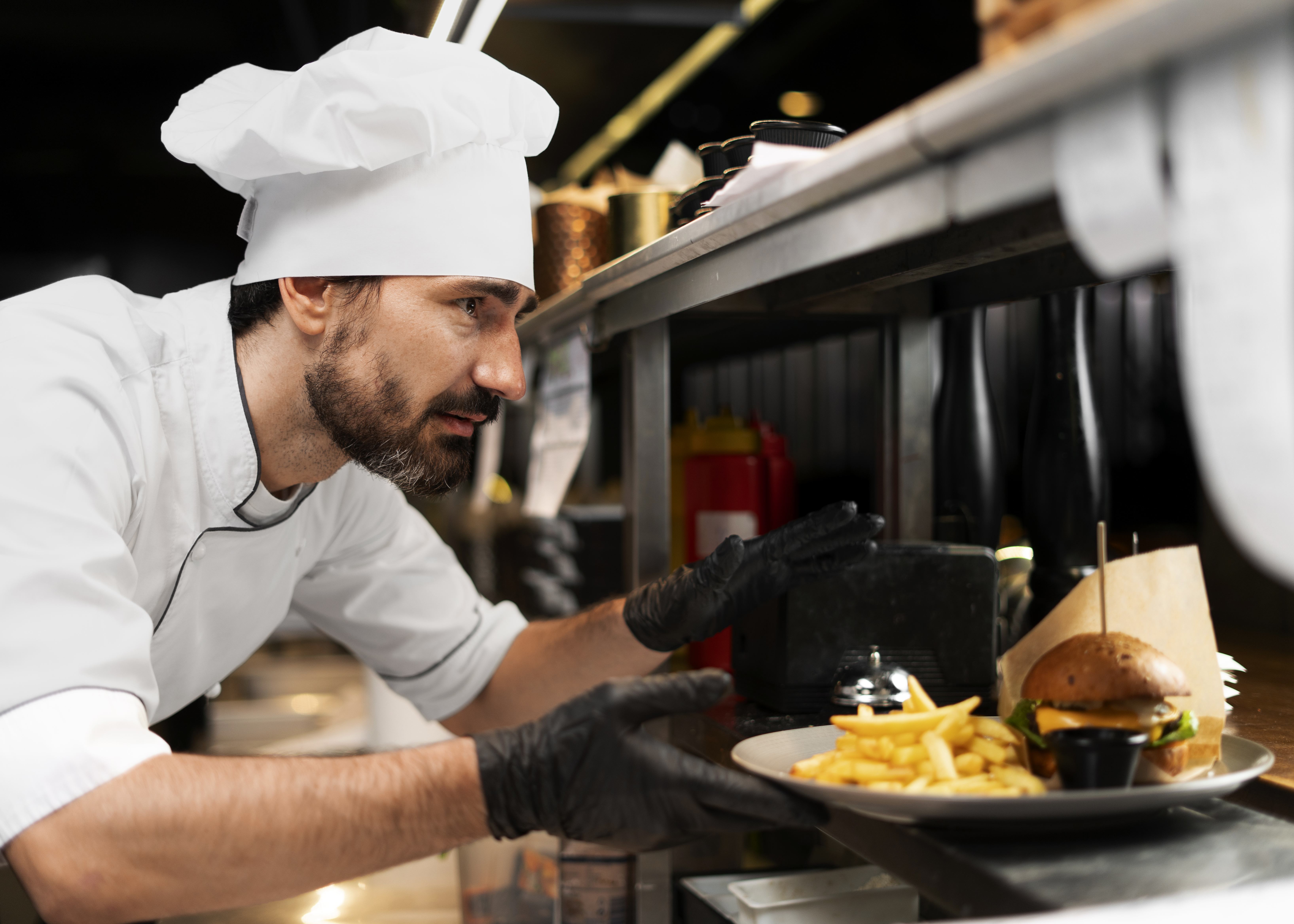 Chef de cozinha preocupado entrega prato de hambúrguer com batatas fritas em uma cozinha comercial, ilustrando o impacto do imposto seletivo no food service em 2027.